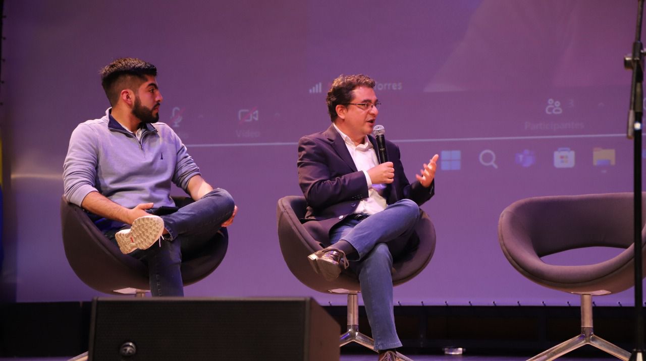 Dos personas participando en un conversatorio en un escenario