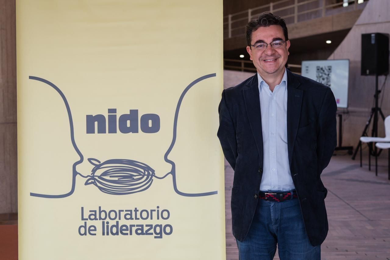 Persona sonriendo junto a un cartel institucional de nido laboratorio